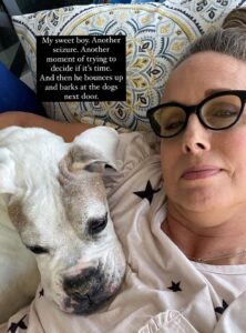 Allison with old white dog resting his head on her chest. 